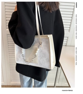 Detail of white tote bag featuring 3D floral textures and a pearl flower charm strap