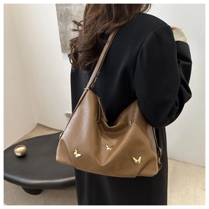Close-up of caramel leather hobo bag with three golden metal butterfly accents