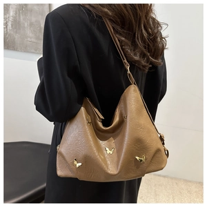 Maillard caramel brown leather shoulder bag with gold butterfly accents on a female model