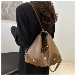Detail of vintage brown leather hobo bag with gold butterfly accents and slim strap