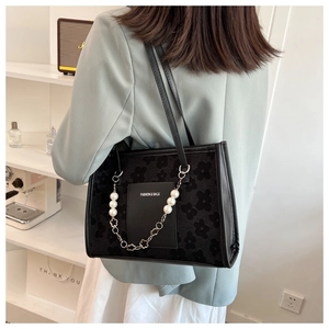 Detail of black floral flocking tote bag with large pearl chain and leather pocket