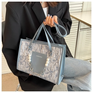 Close-up of light blue bark-textured shoulder bag with elegant pearl chain and logo