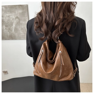 Detail view of the high-quality brown PU leather texture and silver vertical zippers on bag