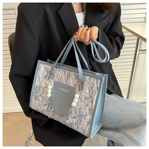Detail of light blue jacquard tote bag with decorative pearl flower chain and leather handles