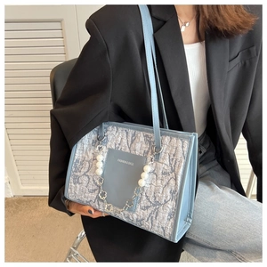 Detailed view of light blue tote bag with pearl and metal flower decorative chain