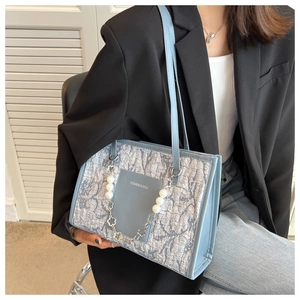 Detail view of light blue tote bag with unique pleated texture and pearl floral chain