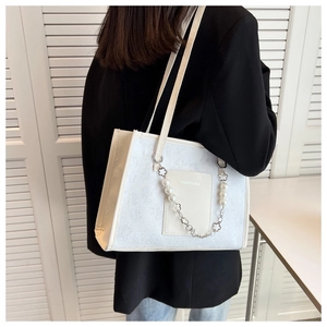 Detail of white floral textured tote bag with elegant pearl and metal flower chain