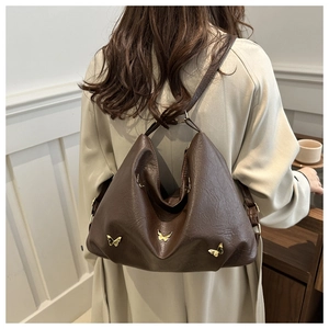 Borsa tote marrone scuro con dettagli a farfalla dorati indossata da una modella