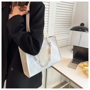 Detail of white jacquard tote bag featuring elegant pearl chain and faux leather straps