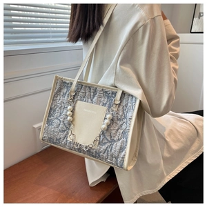 Detail of grey textured shoulder bag with pearl chain and fashion logo on model