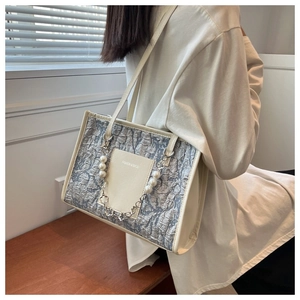 Detail of grey marbled shoulder bag with decorative pearl chain and leather strap