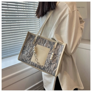 Detail of taupe textured shoulder bag with pearl floral chain and cream pocket