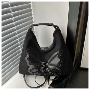 Macro view of black tote bag with butterfly leather applique and metal eyelet lacing