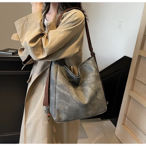 Detail of vintage grey tote bag featuring a brown wide shoulder strap and V-shaped stitching