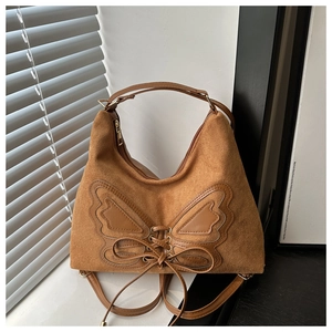 Detailed view of brown suede bag with large butterfly applique and decorative laces