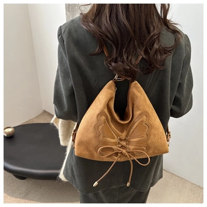 Detail of a brown suede bag featuring a butterfly leather collage and lace-up design