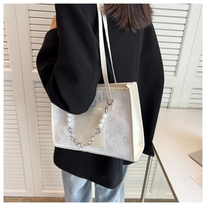 Detail of white embossed floral shoulder bag with decorative pearl and metal chain