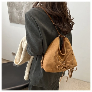 Brown suede tote bag featuring intricate butterfly applique and decorative drawstring ties