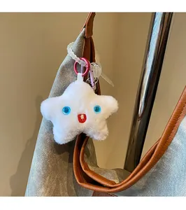 Détail du pendentif étoile en peluche blanche avec yeux bleus sur sac en jean