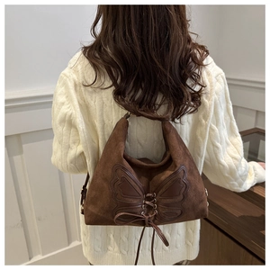 Detailed view of brown suede tote bag featuring a butterfly leather appliqué and lace-up design