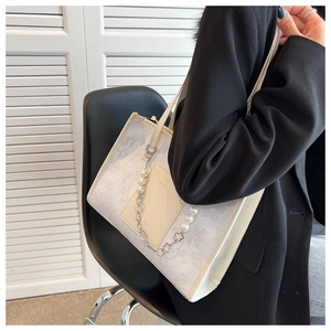 Detail of elegant shoulder bag featuring a pearl chain and textured fabric finish