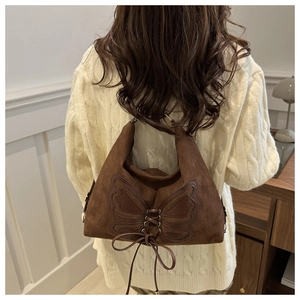 Detail of vintage suede shoulder bag with butterfly stitching and lace-up bow in dark brown