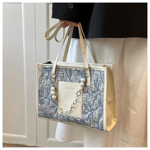 Detail of blue crinkled leather tote bag with elegant pearl and metal flower chain strap