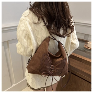 Detail of vintage brown suede tote bag with butterfly embroidery and retro ribbon ties