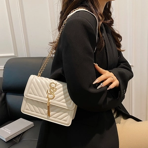 White quilted crossbody bag with gold chain and fringe detail shown on a model