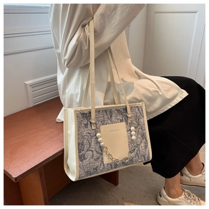 Detailed view of cream-white tote bag with blue texture and pearl metal chain