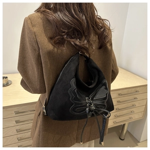 Fashionable butterfly tote bag with leather cross-lace details on model in a cozy room