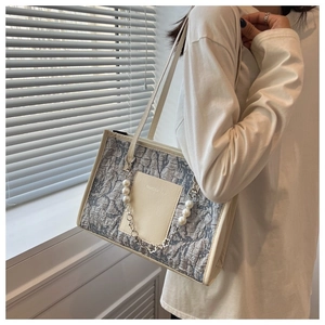 Detail of gray textured tote bag with pearl chain strap and fashion logo plaque