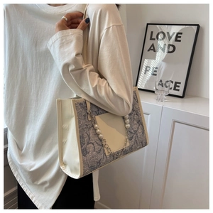 Detail of fabric texture on shoulder bag with decorative pearl and silver metal chain link