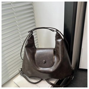 Dettaglio di una borsa tote vintage in ecopelle marrone appoggiata su libri bianchi