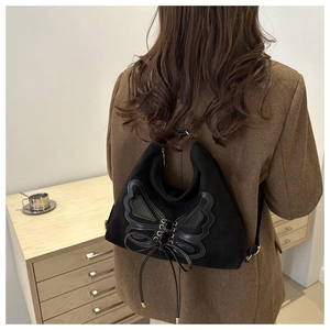 Gothic butterfly wing detail on a black suede backpack showing leather patch and bow