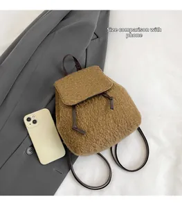 Brown wool mini backpack on a grey jacket next to a smartphone for size comparison