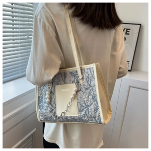 Detail of a large leather tote bag with pearl chain straps and textured patchwork design