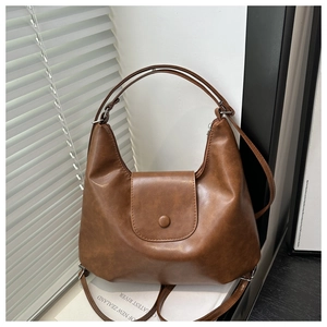 Dettaglio della borsa hobo marrone in pelle PU vintage con fibbia magnetica su bianco