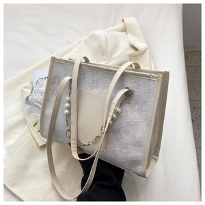 Detail of creamy white tote with floral embossing and decorative pearl chain strap