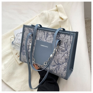 Detail of blue pleated shoulder bag with elegant pearl chain and fashion slogan