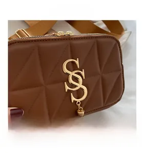 Detail of brown quilted shoulder bag with gold metal SS logo and stylish tassel