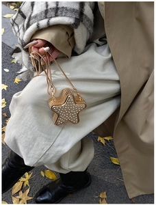 Dettaglio di una pochette dorata a forma di stella con strass scintillanti e tracolla