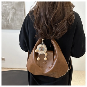 Borsa tote vintage in pelle marrone con ciondolo di peluche portata a spalla del modello