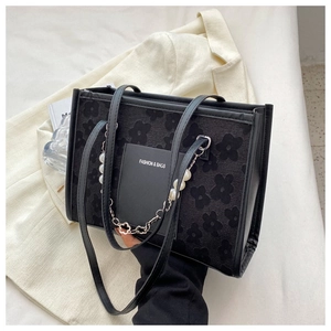 Detail of black floral textured tote bag with pearl chain and silver flower charms