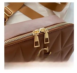 Detail of brown quilted leather bag with dual gold metal zippers and premium hardware