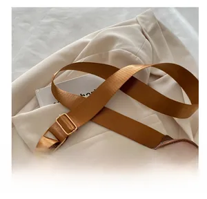 Detail of brown quilted bag with wide woven strap and golden G logo on blazer