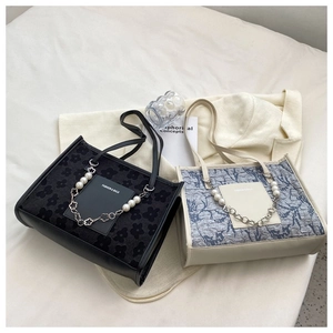 Detail of floral texture and pearl chain handle on stylish tote bags in soft lighting