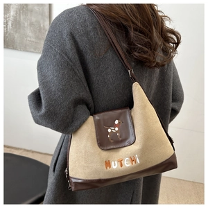 Detail of a retro canvas crossbody bag featuring a cartoon dog embroidery and leather trim