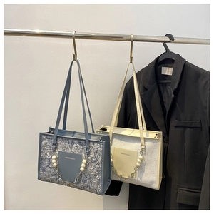 Detail of ruched fabric texture and pearl flower chain on stylish shoulder bags