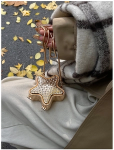 Detail of star-shaped evening clutch bag featuring sparkling rhinestones and a gold chain